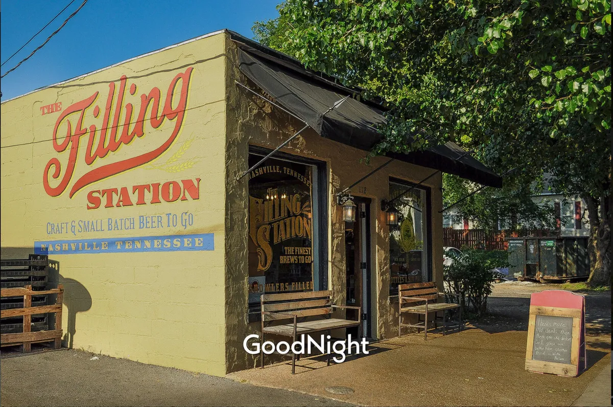 A cheerful exterior view of The Filling Station with a colorful storefront, visible outdoor seating area, and signage. The image captures patrons relaxing and socializing over drinks in a welcoming neighborhood spot.