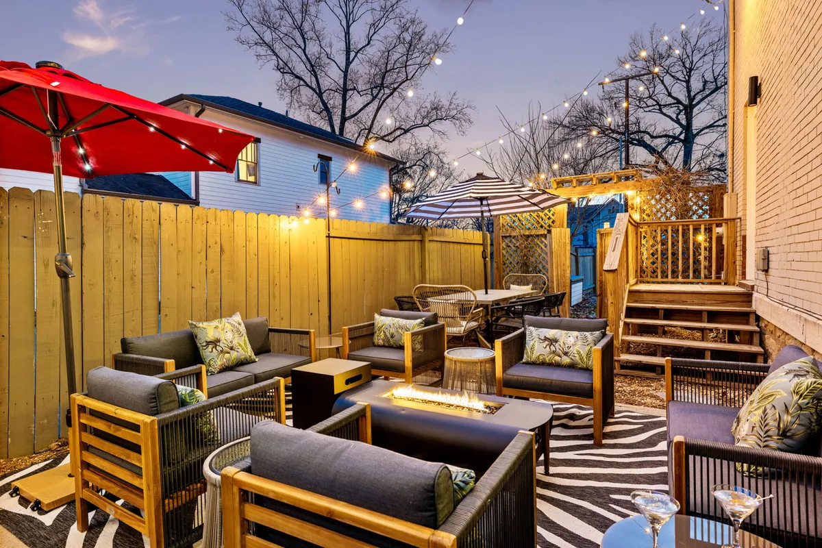 A welcoming backyard setup with lounge seating, decorative umbrellas, string lights, and a zebra rug offers the perfect space for family gatherings or relaxing evenings under the stars. The festive yet cozy mood reflects the home’s private outdoor amenities.