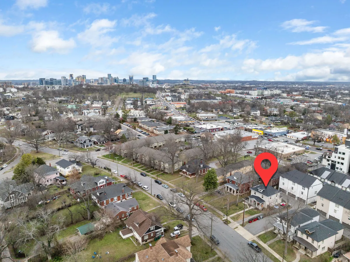 An inviting exterior view showcasing the city skyline with residential houses, tree-lined streets, and open green spaces, suggesting a prime location and easy access to urban amenities.